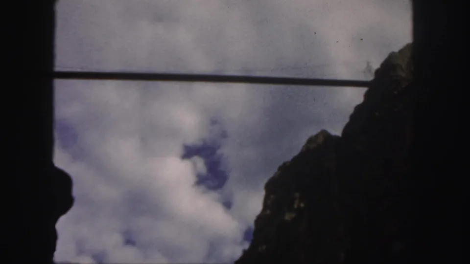 1958 Colorado home-movie view of a clouded sky and rocky terrain partially obscured by a dark frame and horizontal line.
