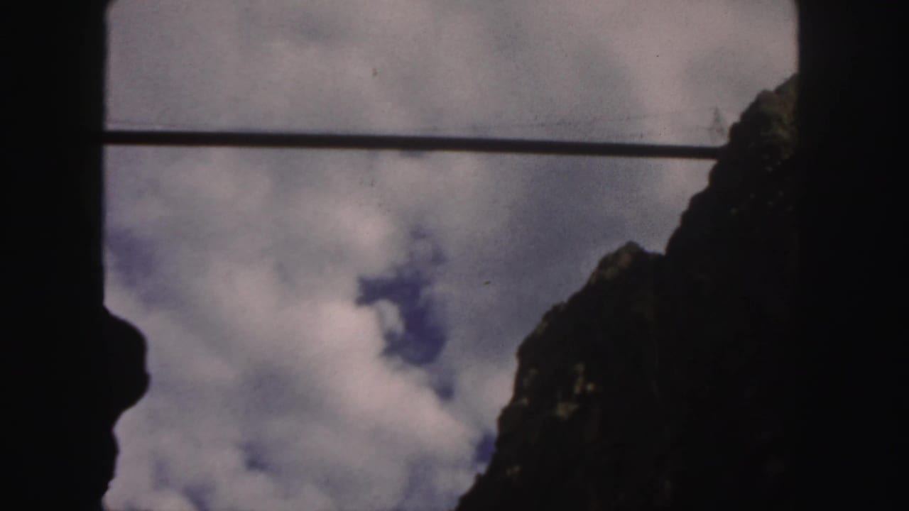 Dark mountain peaks frame cloudy sky with a thin horizontal cable across the view.