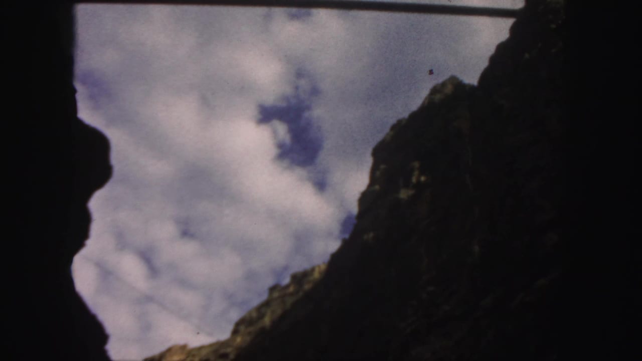 Dark foreground framing a cloudy sky and steep rocky cliff.