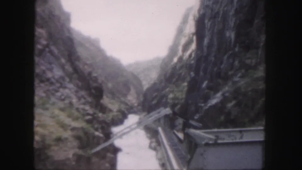 Colorado home-movie frame from 1958 showing a soft, elevated view into a narrow canyon from a bridge.