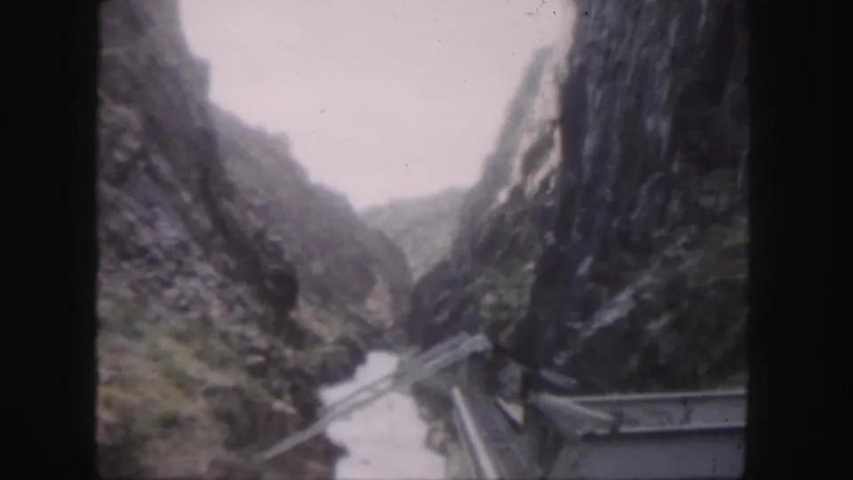 Soft 8mm travel frame showing the rocky Colorado canyon and bridge structure from an elevated crossing point.