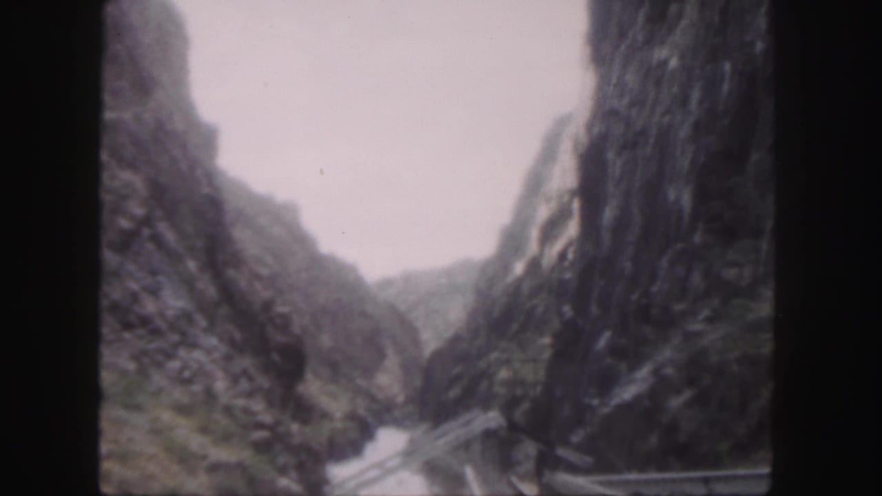 1958 Colorado 8mm frame showing a narrow river through steep rocky walls, with a cable or bridge-like structure spanning the canyon.