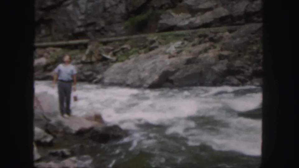 The final frame holds on the man standing by the powerful Colorado river current, with boulders and foaming water around him.