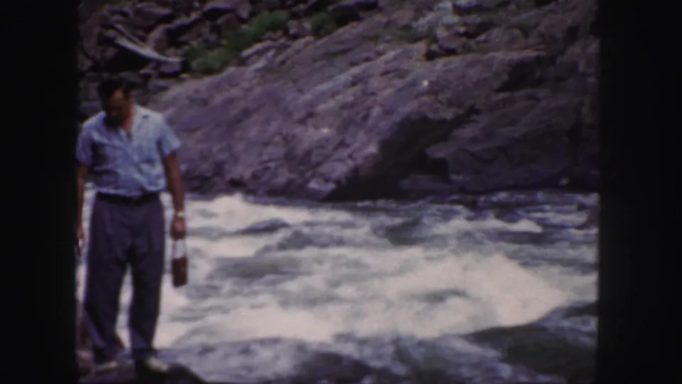 The final frame shows the man looking downward near the rapids, with dark rocks and whitewater in the background.