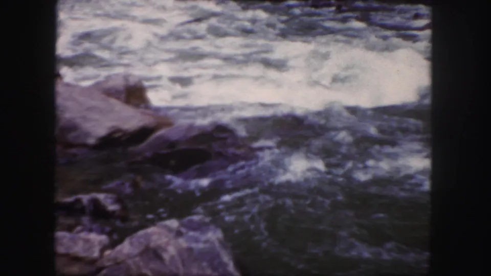 1958 Colorado 8mm frame focused on whitewater and boulders, with no clear person visible in this crop.