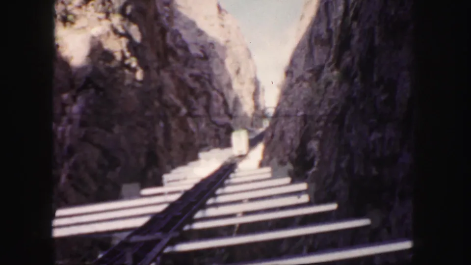 1958 Colorado rail-route view showing tracks, pale ties, and steep canyon walls from a moving passenger perspective.