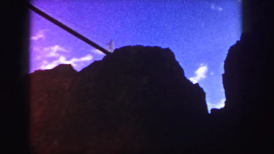 1958 Colorado 8mm frame with dark rock or temple-like silhouettes under a vivid purple-blue sky and a diagonal cable or rail.