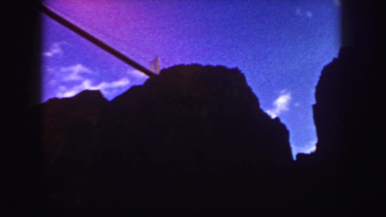 Similar silhouetted forms beneath a saturated sky, framed by dark vertical film edges.