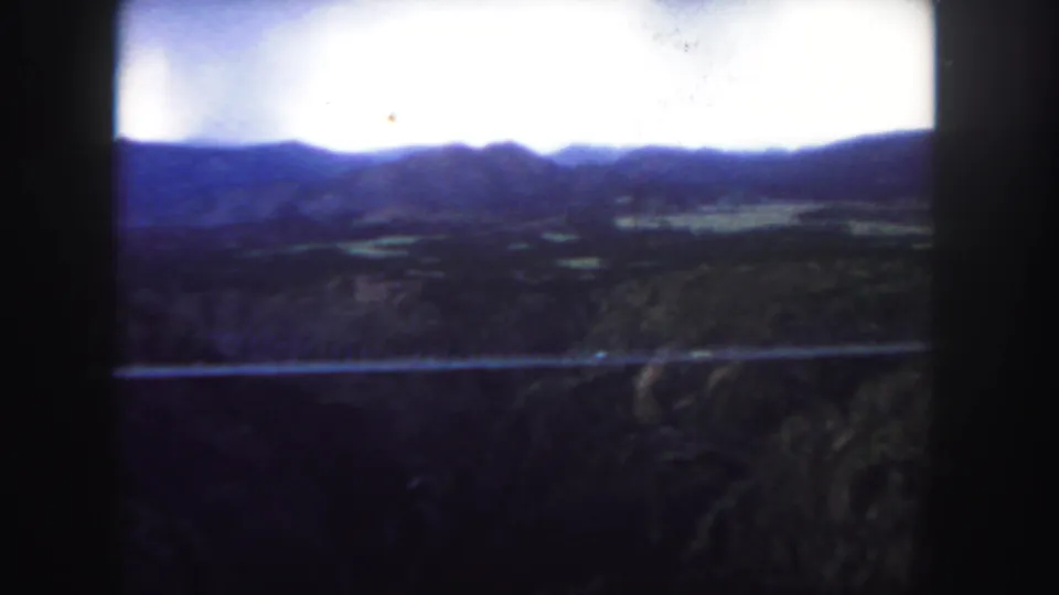 Colorado 1958 8mm frame with the bridge stretched across the canyon and soft blue ridges in the distance.