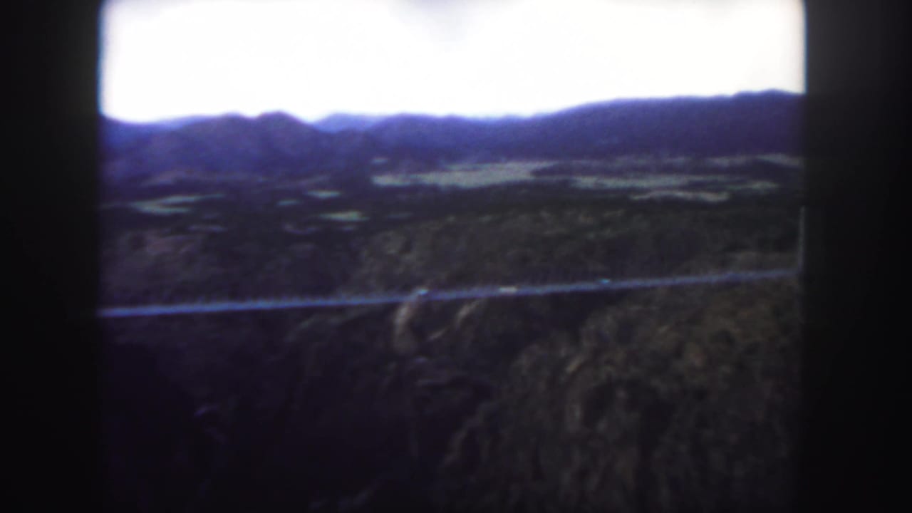 Suspension bridge seen across a canyon with mountains in the background.