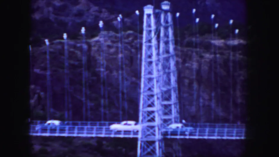 Close view of a Colorado canyon bridge in 1958, with lattice towers, railings, and small cars crossing the span.