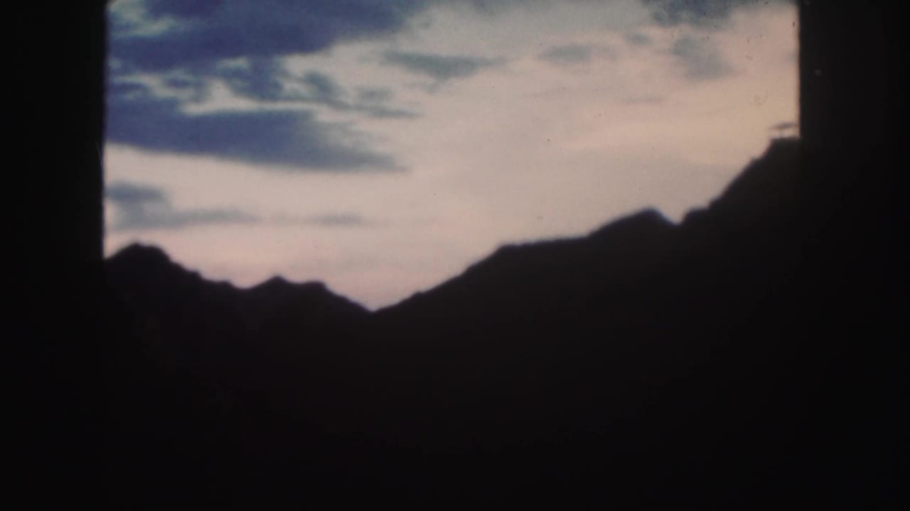 Clouds over a dark mountain ridge, with heavy black edging on both sides.