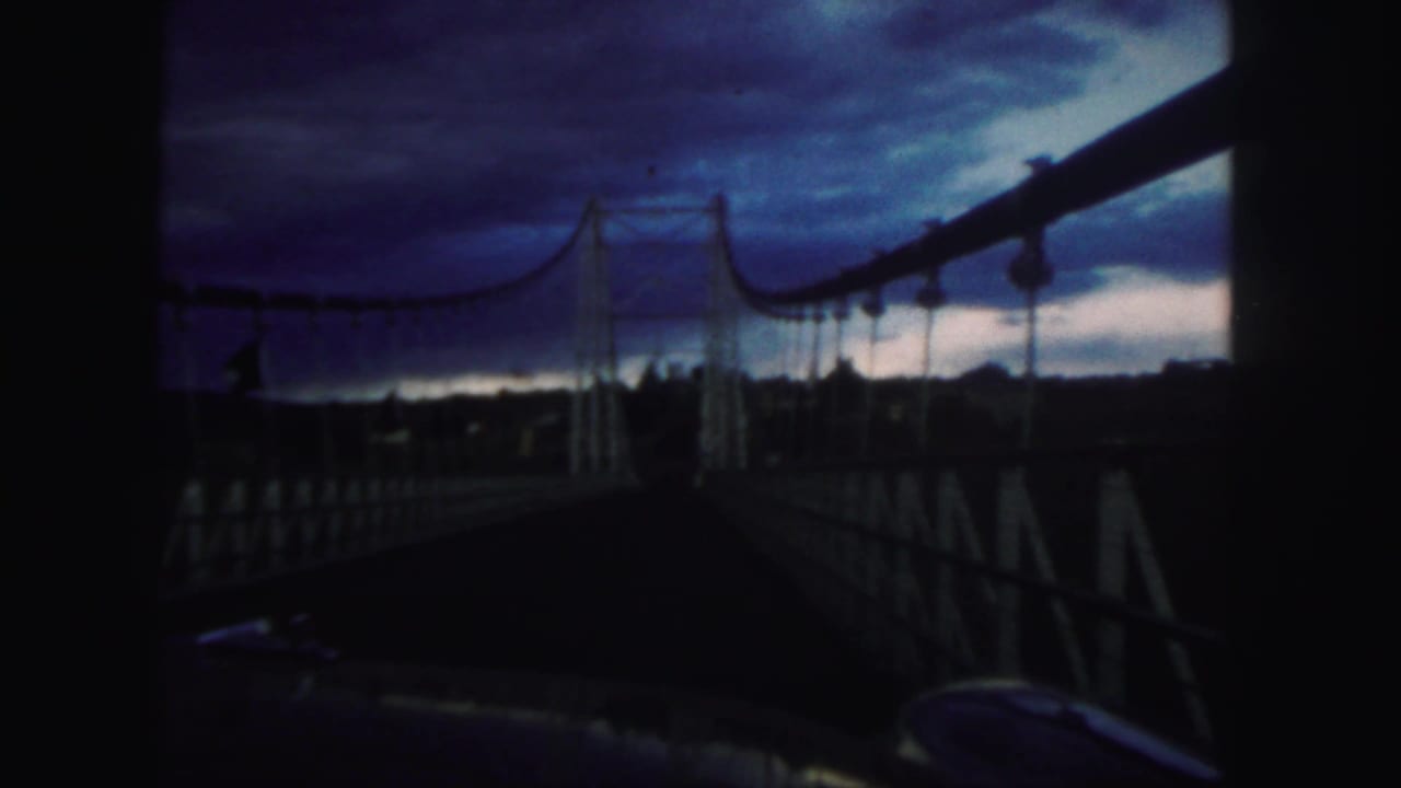 Suspension bridge walkway under a dark blue evening sky.