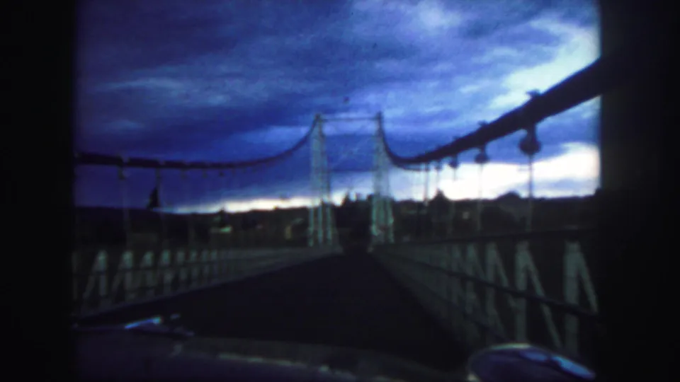 Colorado 1958 frame of the suspension bridge structure silhouetted against a blue-purple evening sky.
