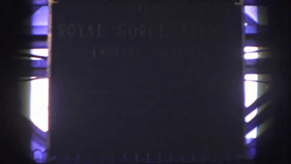 End frame of the 1958 8mm close-up, showing the Royal Gorge Bridge plaque in low exposure with bright structural openings nearby.