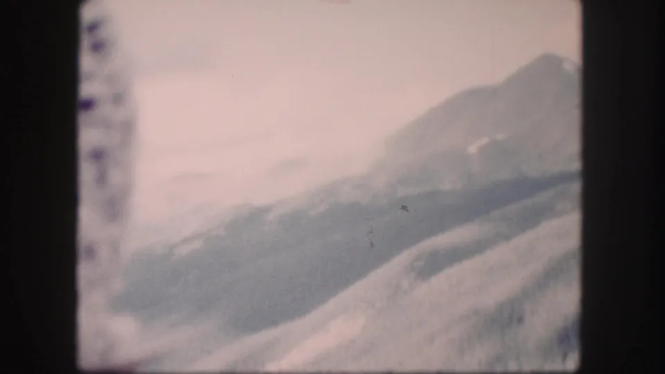Faded 8mm Colorado landscape frame with mountain ridges, a pale sky, and visible film-edge markings.