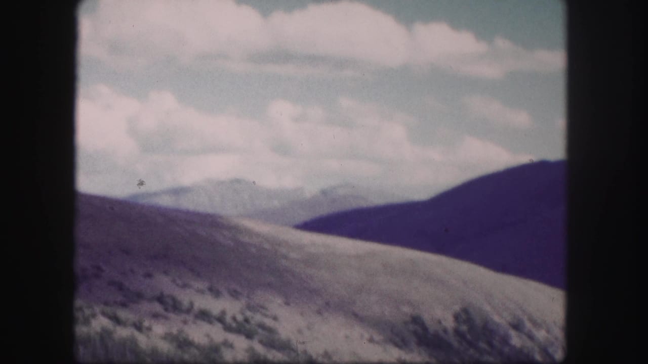 Open hills with distant peaks and clouds in the background.