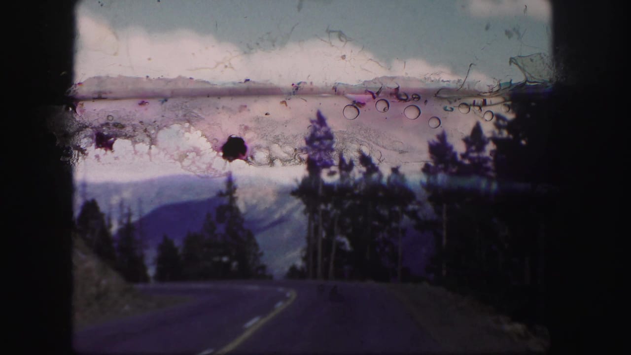Curving mountain road with pine trees and distant ridges.
