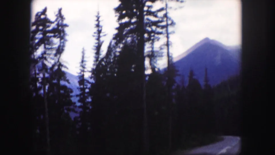 The final frame shows a Colorado mountain road bordered by evergreens, with a pointed peak beyond the forest.
