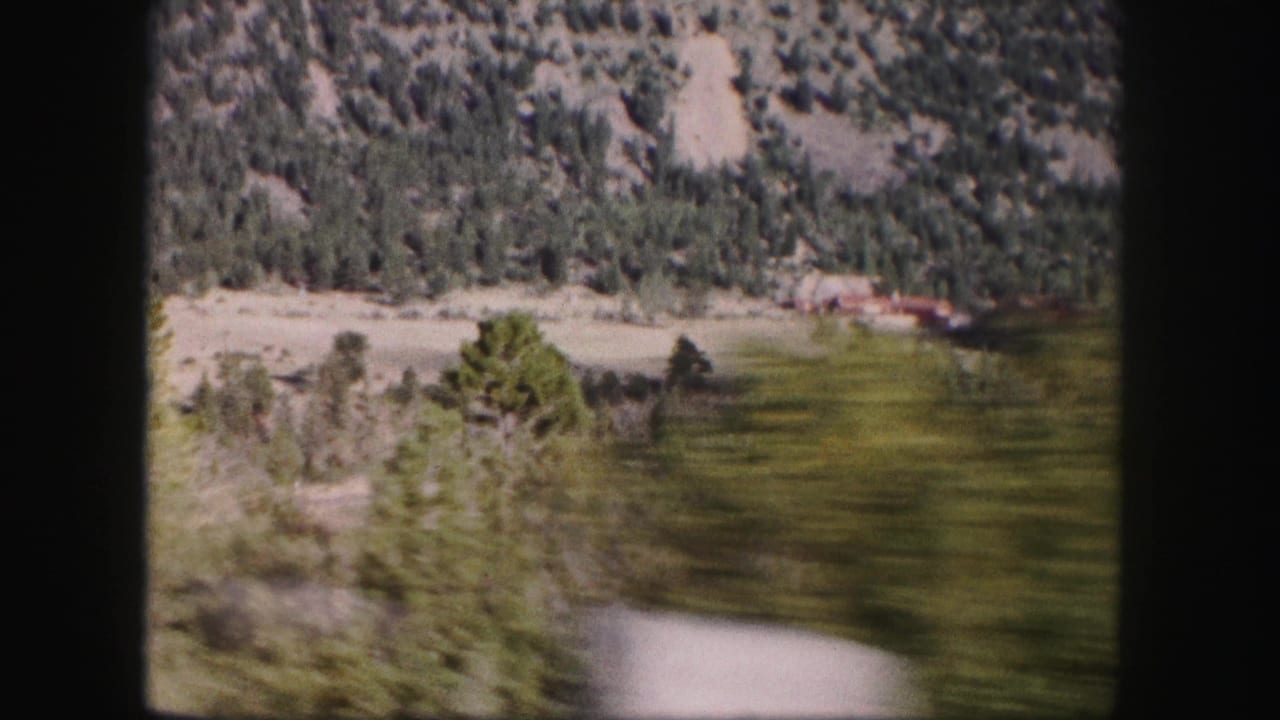 Blurred roadside trees and valley slopes viewed through a window.