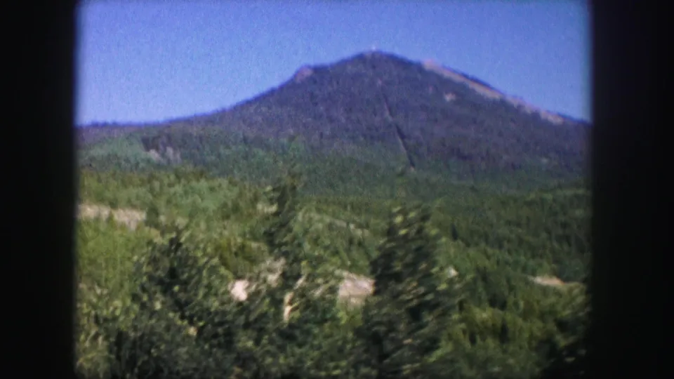 A second 1958 Colorado view of the same forested mountain, with evergreen slopes and visible 8mm frame edges.