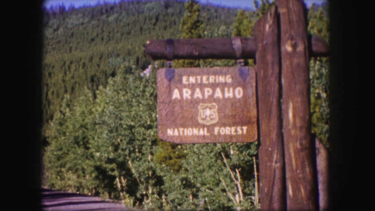 Arapaho National Forest entrance sign beside trees and timber posts.