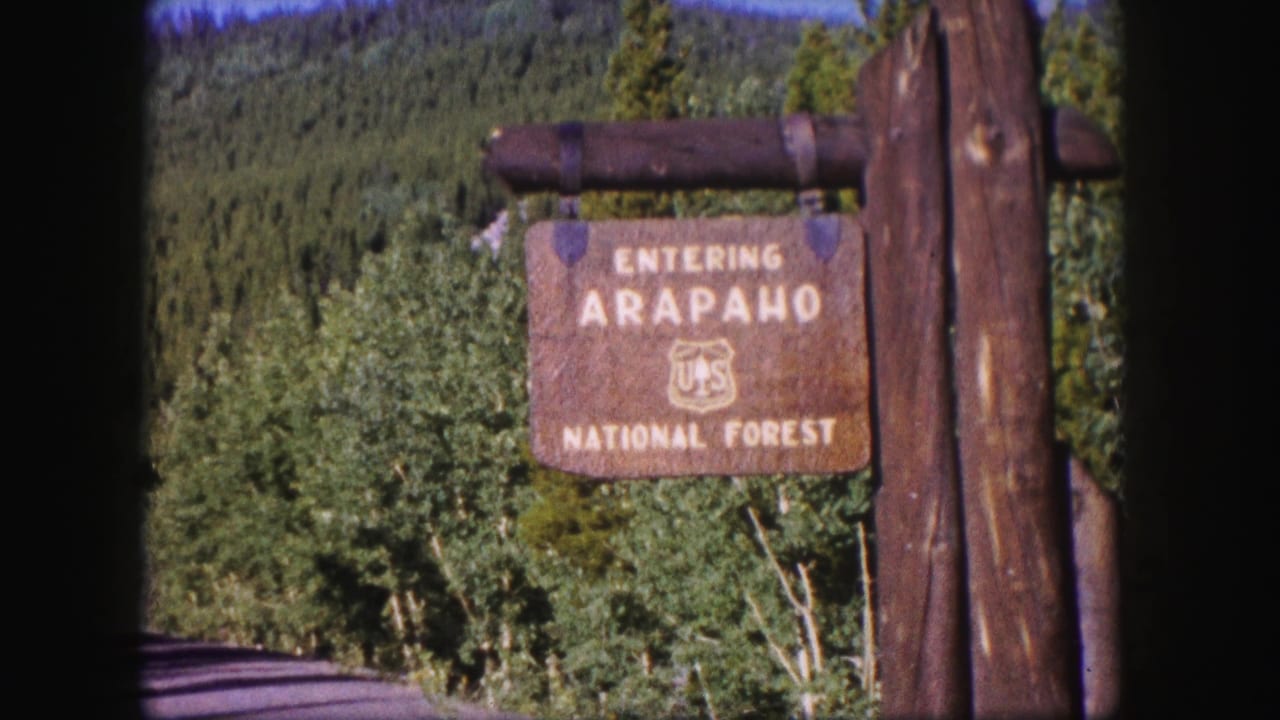 Arapaho National Forest sign with forested hillside in the background.