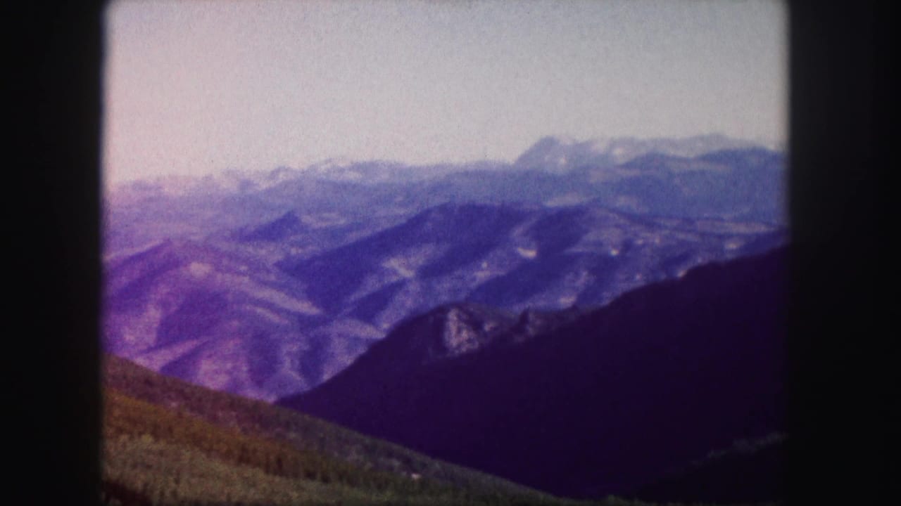Distant mountains and dark foreground slopes seen through the edge of an 8mm film frame.