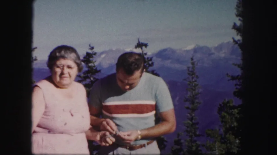 The older woman faces the camera while the man looks down at his hands at a Colorado mountain overlook in 1958.