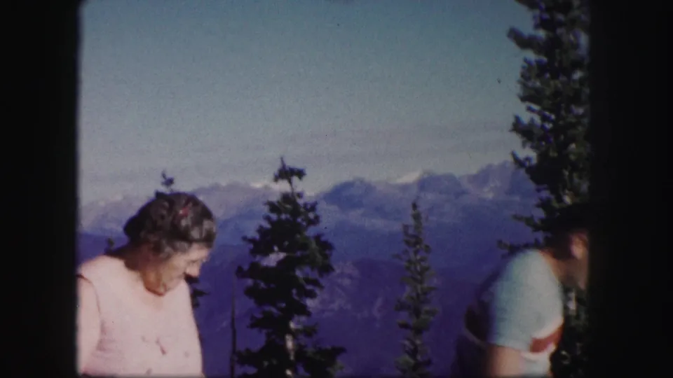 The woman remains near the overlook while the man moves partly out of frame, leaving more of the Colorado mountain landscape visible.