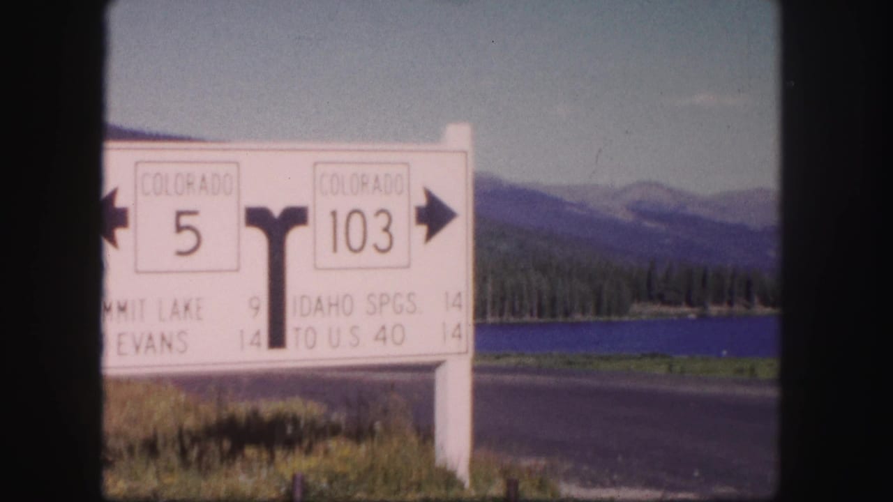 Colorado highway sign beside a lake and mountain range.