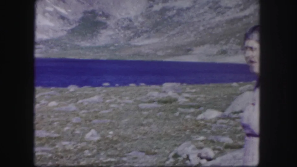 The frame catches part of the woman's face and upper body near a deep blue mountain lake in the Colorado high country.