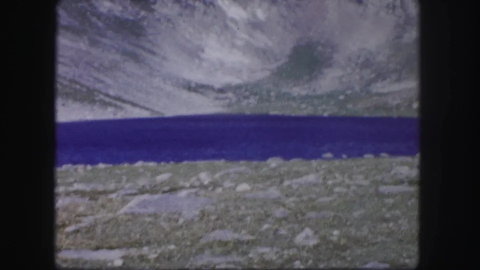 The clip ends on a scenic 1958 Colorado view of blue alpine water, rocky shoreline, and steep mountain slopes with snow patches.