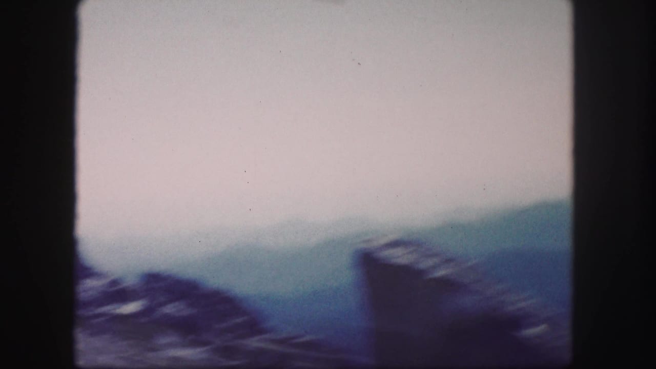 Hazy mountain ridges under a pale sky with dark film borders.