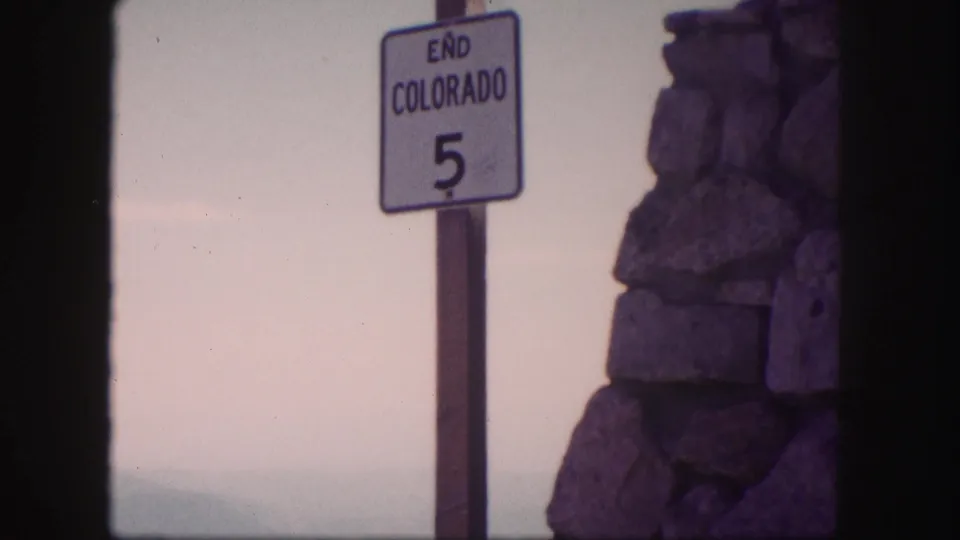 A roadside sign reading END COLORADO 5 appears beside a stone wall in the 1958 Colorado travel footage.