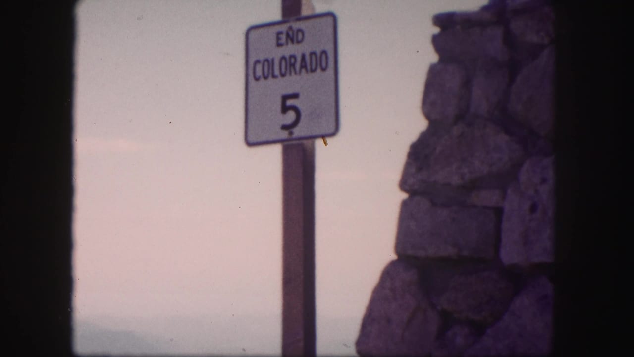 Colorado road sign reading END COLORADO 5 appears beside a stone structure, with the scan showing dark frame borders.
