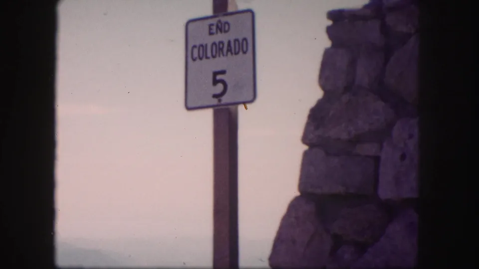 Colorado road sign reading END COLORADO 5 appears beside a stone structure, with the scan showing dark frame borders.