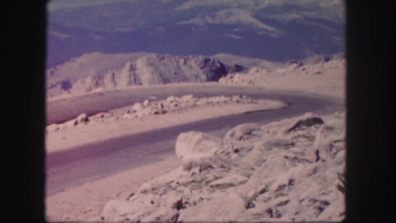 Curved road and rocky hillsides seen through black film borders.