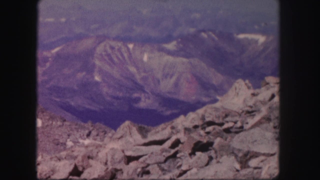 Gray rock formations in front of hazy mountain ridges and a muted sky.