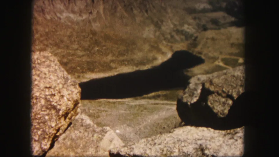 1958 Colorado home-movie view of a dark shadow crossing sunlit rocky terrain near the end of a hike.