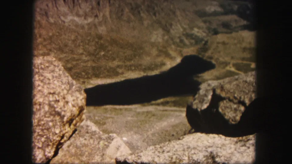 Warm-toned 1958 Colorado 8mm footage showing rocky mountain ground, shadow, and soft archival grain.