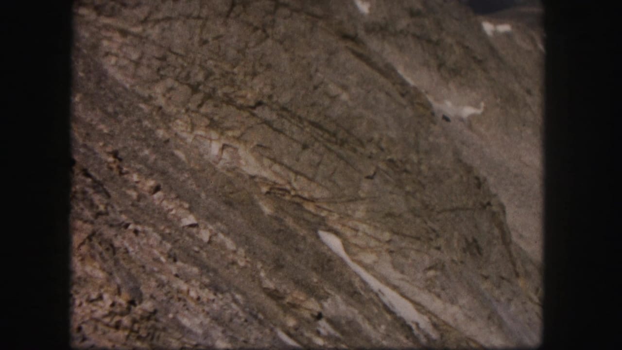 Close view of steep layered mountain rock with small snow patches.