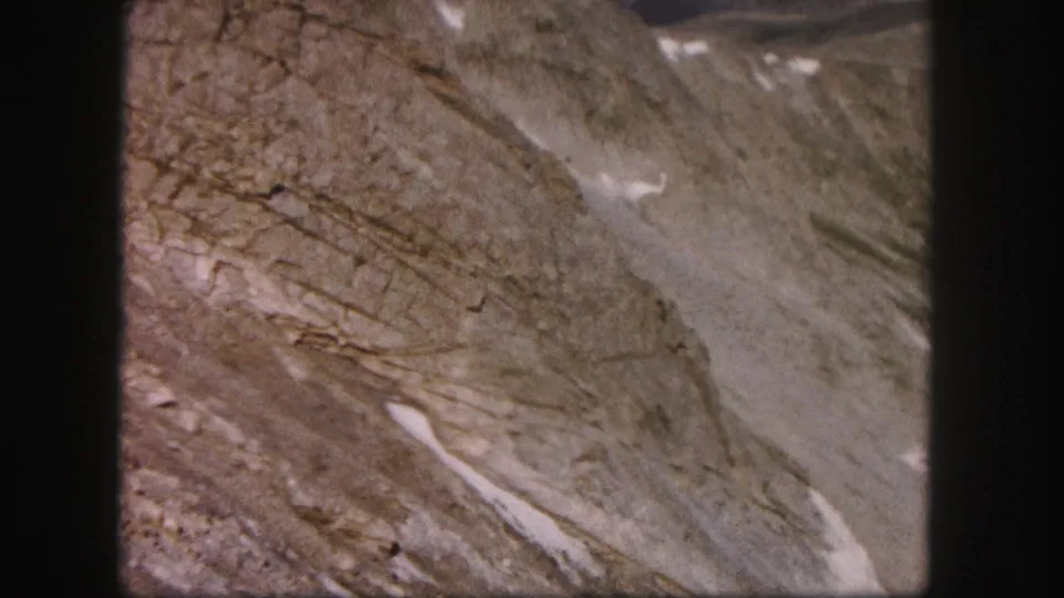 The final frame lingers on a Colorado rocky slope with visible layered texture, scree, and small snow patches in 8mm color.