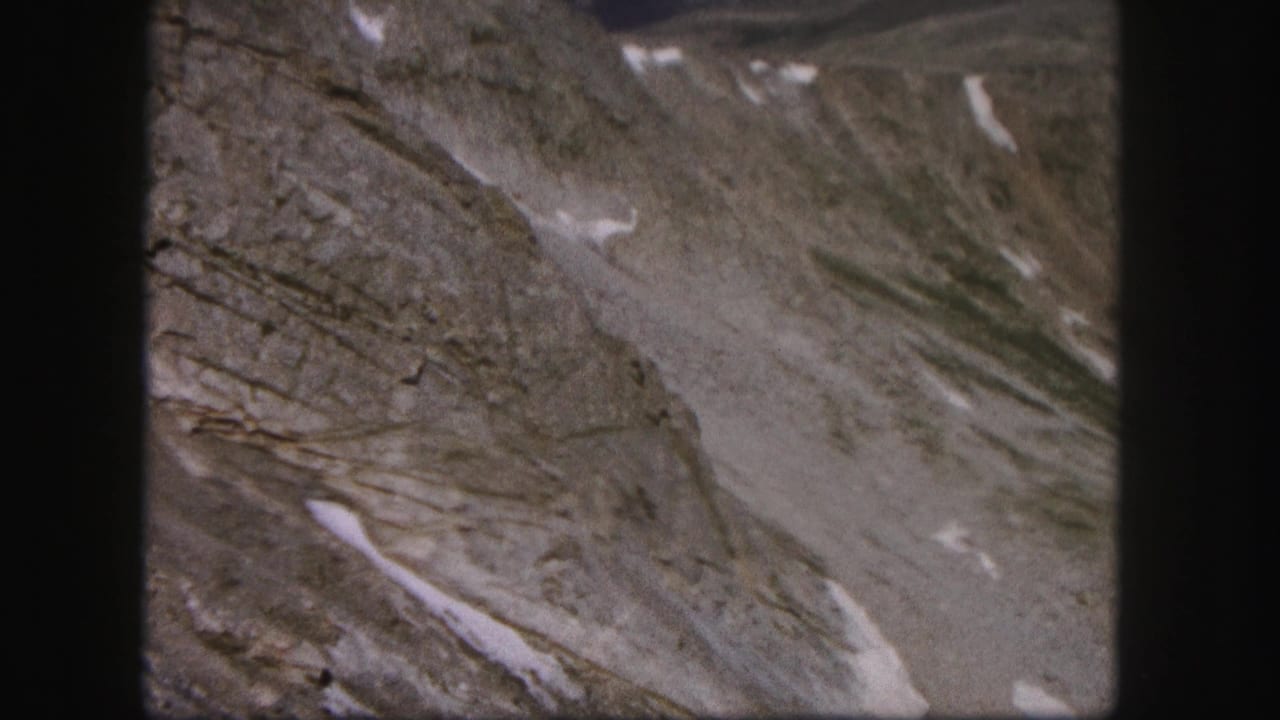 Bare mountain terrain with snow streaks and muted rocky textures.