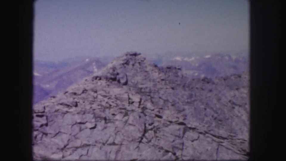 Colorado 8mm mountain view with a rocky summit in front and layered, hazy ridges across the background.