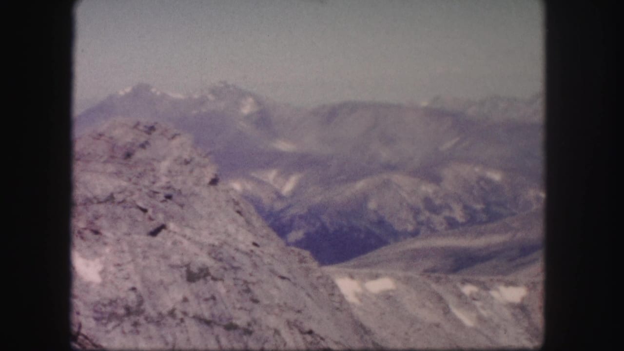 Distant mountain peaks beyond a rocky slope in daylight.