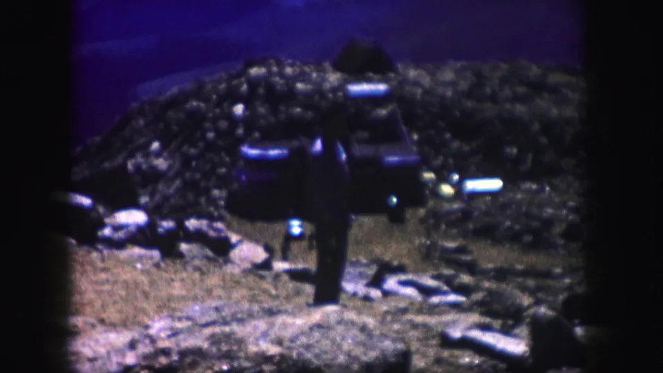 1958 Colorado 8mm frame with dark rocky terrain, a shadowed vehicle-like shape, and low-light color shifts at dusk or night.