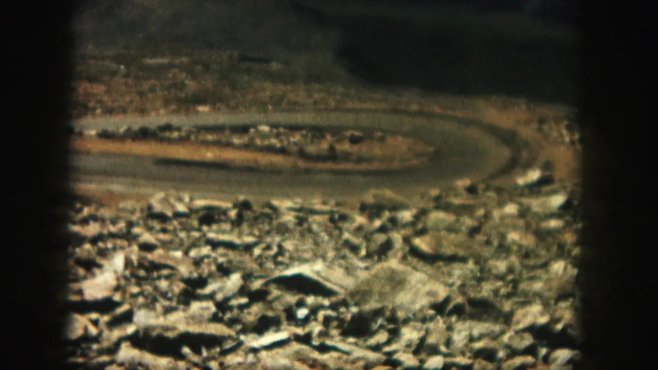 The road bends across open rocky terrain in Colorado, with soft focus and color shift typical of scanned 8mm home movies.