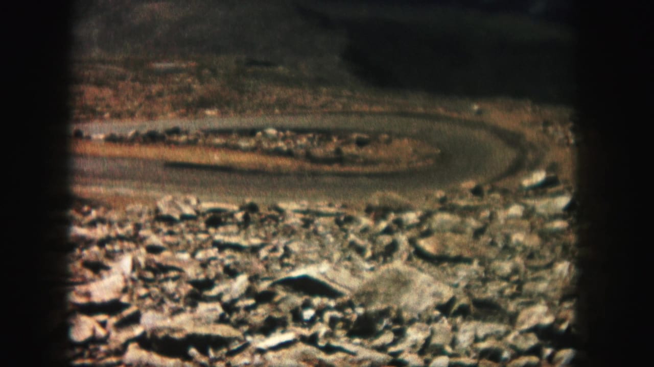 Distant curved road beyond a rocky foreground in a dry landscape.