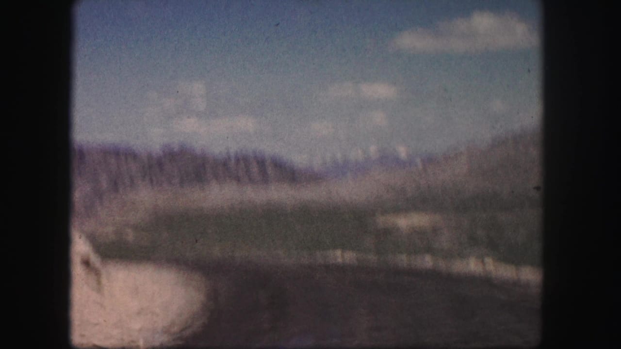 Soft, distant view of a pale road or valley seen through dark film-frame edges.